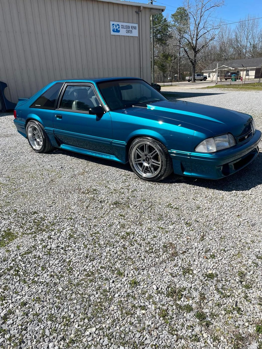 Fox-body Mustang finished in metallic teal outside the shop